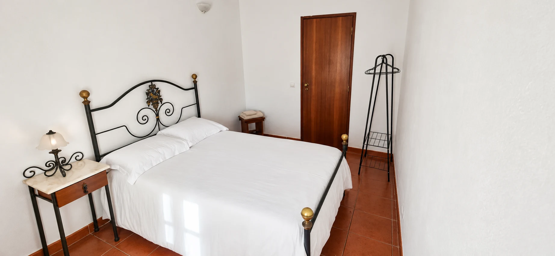 Quarto com cama de ferro e roupa branca